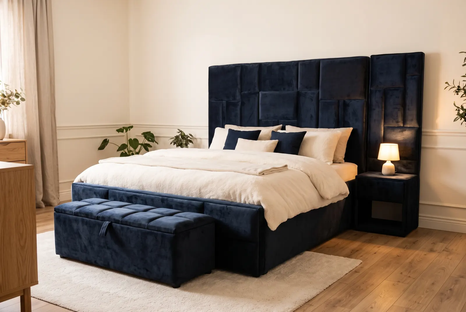 A navy velvet bed with a tall headboard of staggered panels, a side tower and a tufted storage bench at the foot
