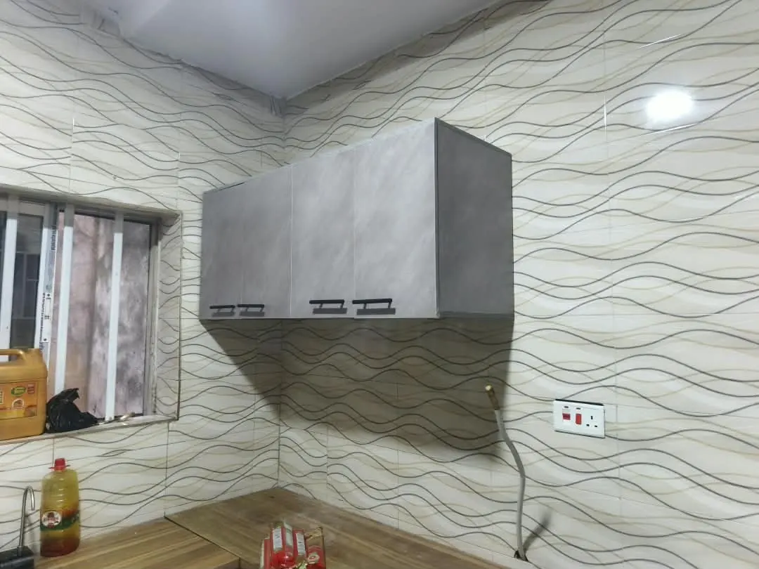 A grey wall-mounted kitchen cabinet over a hob on a wave-pattern tiled wall