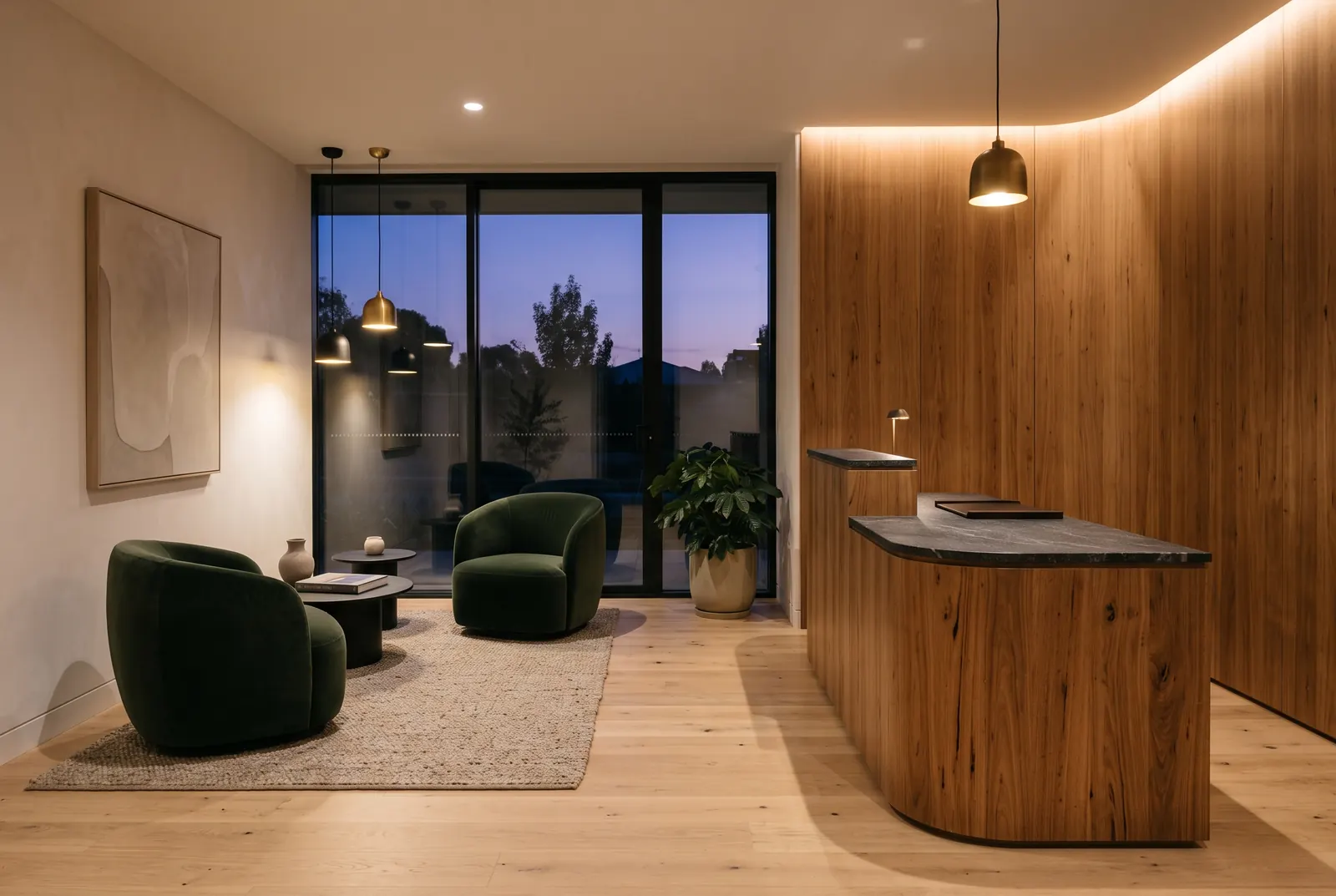 A reception area with a curved wood counter and two green velvet armchairs